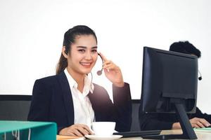 mujer asiática del personal de negocios joven que trabaja con auriculares y computadora para obtener apoyo. foto