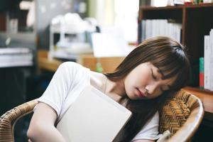 descanse la mujer adolescente asiática cansada y sostenga la tableta relájese durmiendo. foto