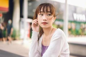 Asian teenager college student woman use earphone listening music at outdoor. photo