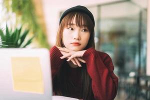 Asian teenager college student woman wear red sweater using laptop for study online photo