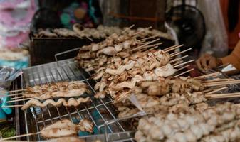 Vendor skewers of squid grilled on charcoal. photo