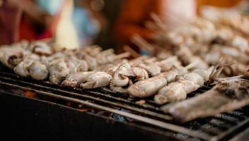Vendor skewers of squid grilled on charcoal. photo