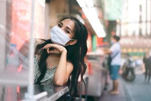una mujer adulta asiática feliz usa una máscara protectora para una nueva vida normal. foto