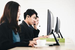 Positive smile young business staff asian man using headphone and computer for support photo