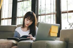 mujer adolescente asiática aprendiendo y leyendo libros con laptop. foto