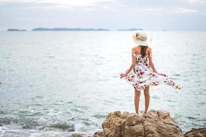la mujer asiática turística adulta se pone de pie siéntase libre y mira al mar. foto