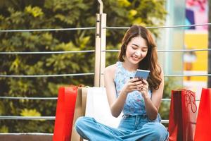 Asian woman sit with red bags and using smartphone photo
