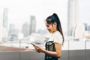 Young business adult asian woman using mobile phone for online dating app text and chat blur city background.