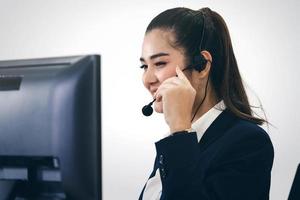 mujer asiática del personal de negocios joven que trabaja con auriculares y computadora para obtener apoyo. foto