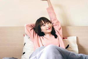 Despierta estirar el brazo mujer adolescente asiática en el dormitorio. foto