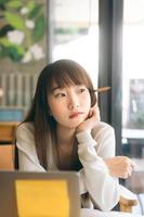 Asian teenager college student woman study and work online at cafe on day. photo