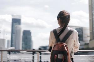 vista trasera de una joven estudiante universitaria adulta que usa suéter y mochila de color rosa el día. foto