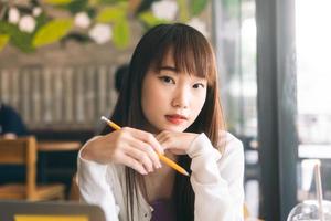 Portrait of young adult asian college student woman studying at cafe.