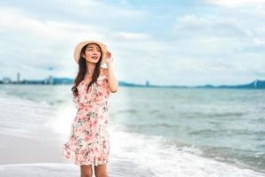 mujer joven asiática caminar y relajarse en la playa foto