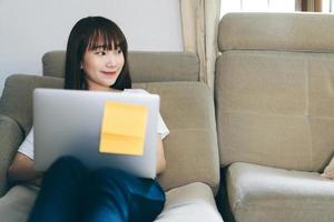 mujer adolescente asiática aprendiendo y examinando a través de internet con laptop. foto