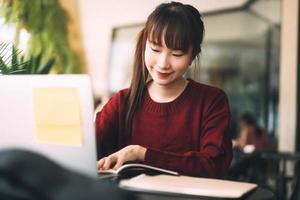 mujer adulta joven estudiante universitaria asiática con computadora portátil para estudiar en el café el día de invierno.