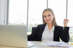 A beautiful business woman in a suit, neatly dressed, sitting in the office with a bright smile photo