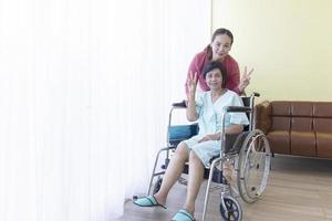 The Asian family raised two fingers, the sick mother, sitting in a wheelchair, treated in a hospital, and had a daughter to take care of closely. photo