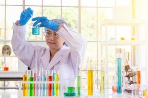 Discovering a cure for an Asian female scientist who is concentrated, holding a test tube and watching while working. photo