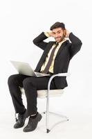 A handsome businessman sitting in a good smile on a chair and having a tablet isolated on white background, photo