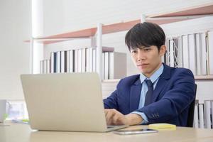 un joven hombre de negocios asiático se sentó seriamente en el escritorio de la oficina.