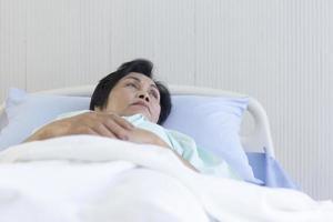 The elderly Asian woman lay in bed and recuperated in the hospital. photo