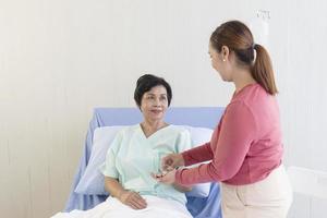 una anciana asiática está siendo atendida por sus familiares en la sala de recuperación del hospital.