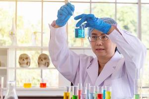 Discovering a cure for an Asian female scientist who is concentrated, holding a test tube and watching while working. photo