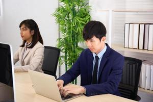 dos hombres de negocios y mujeres de negocios se sientan diligentemente en la oficina. foto