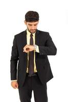 A handsome young man stood looking at his watch isolated on a white background. photo