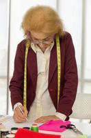 Elderly female designers sketching on paper to design clothes photo