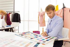 Professional team work designers, young men and elderly women in the office with a variety of fabric tones and equipment for various designs. photo