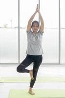 mujeres asiáticas de mediana edad hacen ejercicios de yoga en colchonetas de goma en el gimnasio. foto