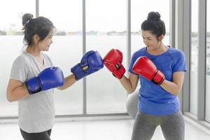 dos mujeres asiáticas de mediana edad haciendo ejercicios de boxeo en el gimnasio.