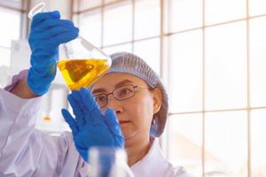 Discovering a cure for an Asian female scientist who is concentrated, holding a test tube and watching while working. photo