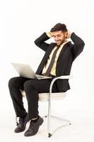 A handsome businessman sitting in a good smile on a chair and having a tablet isolated on white background, photo