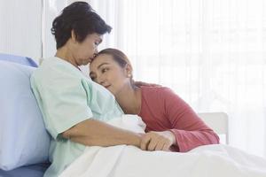 An Asian daughter takes care of her sick mother on a bed in a hospital. photo