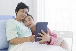 The sick mother lay on the bed in the hospital and her daughter beside each other was making video calls in a happy manner. photo