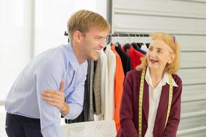 Designer smiling elderly woman's clothing Laughing with male customers photo