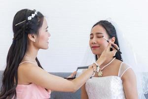 una maquilladora está maquillando a una novia asiática para su boda.