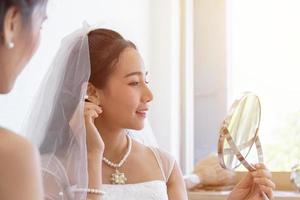 una novia asiática está maquillada, peinándose para su boda.