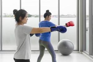 Two middle-aged Asian women doing boxing exercises in the gym. photo