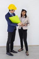 Two Asian male and female foreman wearing a helmet and standing and talking at the event site photo