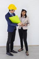 dos capataces masculinos y femeninos asiáticos con casco y de pie y hablando en el lugar del evento foto