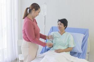 An elderly Asian woman is being taken care of by her relatives in the hospital recovery room. photo