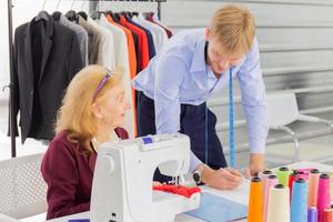 Professional designers, young men and elderly women in the workroom with various fabric color schemes photo