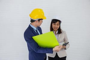 Two Asian male and female foreman wearing a helmet and standing and talking at the event site photo