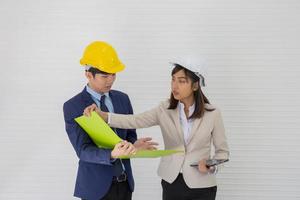 dos capataces masculinos y femeninos asiáticos con casco y de pie y hablando en el lugar del evento foto