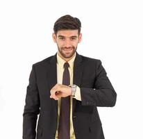 A handsome young man stood looking at his watch isolated on a white background. photo