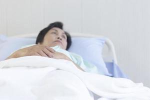 concepto asiático anciana acostada en la cama y recuperarse en el hospital. foto
